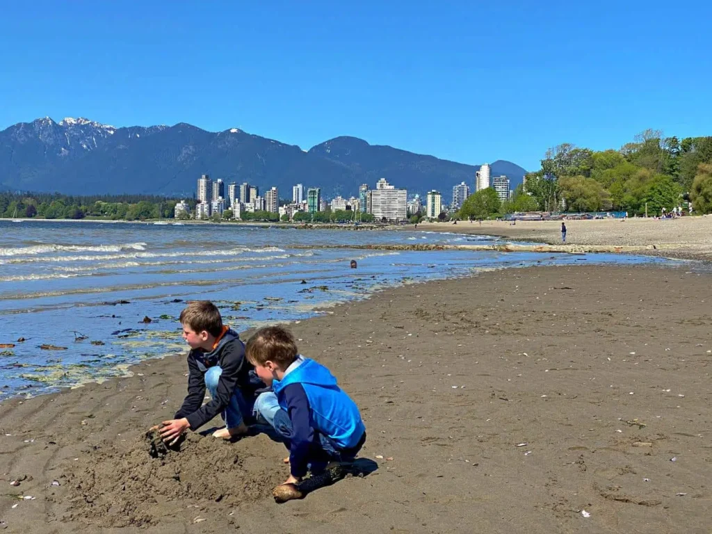 two boys digging in sand on kitsilano beach in vancouver