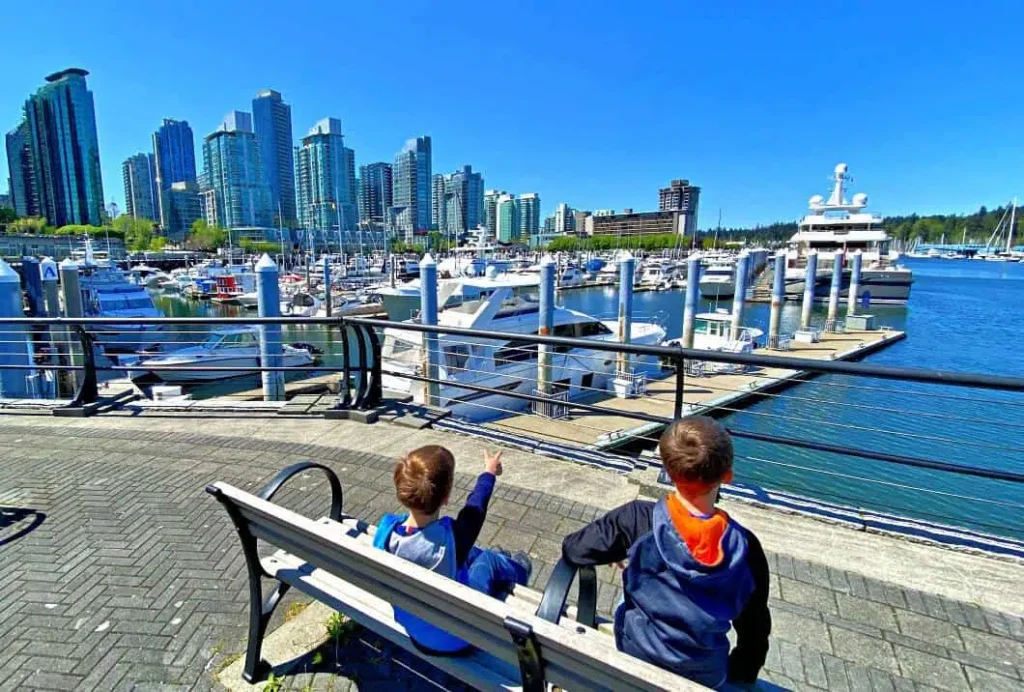two boys sitting on a bench looking at marina in vancouver british columbia