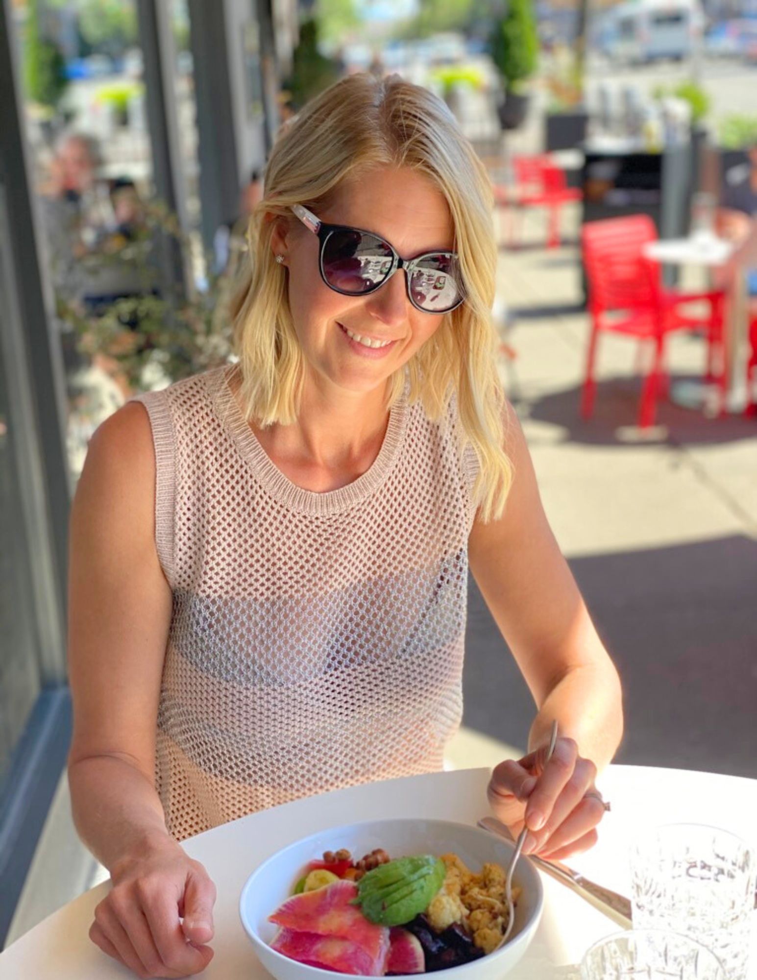 woman wearing sunglasses eating on patio