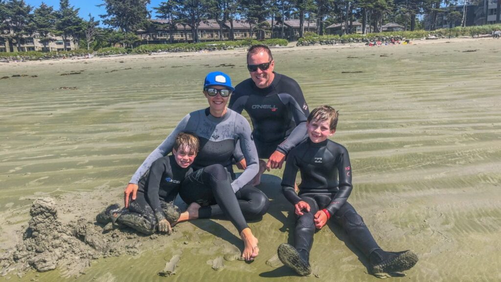 family on beach wearing wetsuits