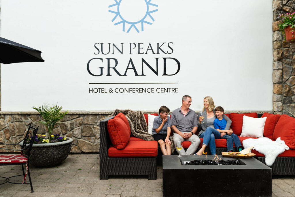 family laughing on red couch at sun peaks grand hotel in sun peaks british columbia