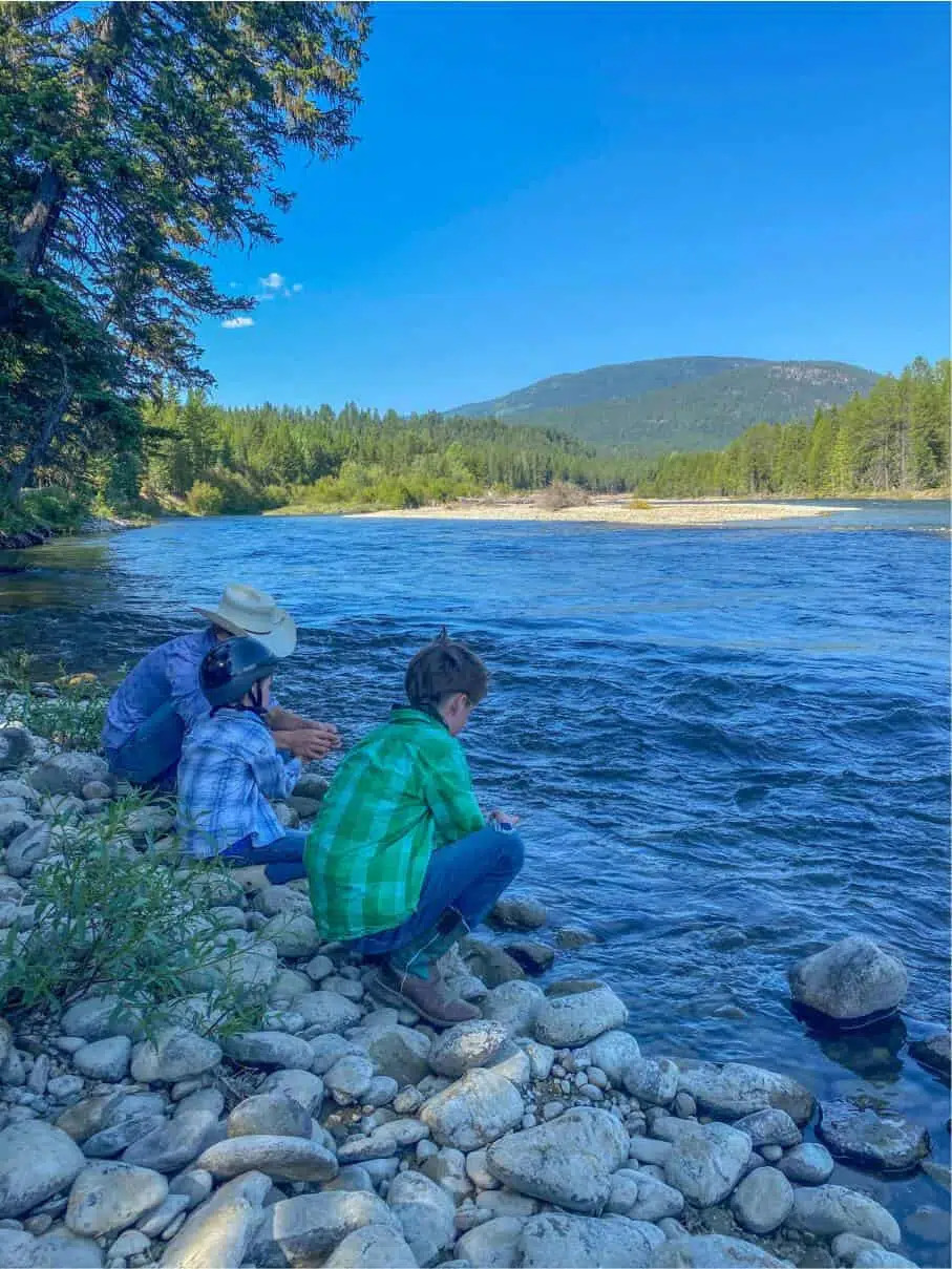 two boys and woman skipping rocks at the lake in the kootenays