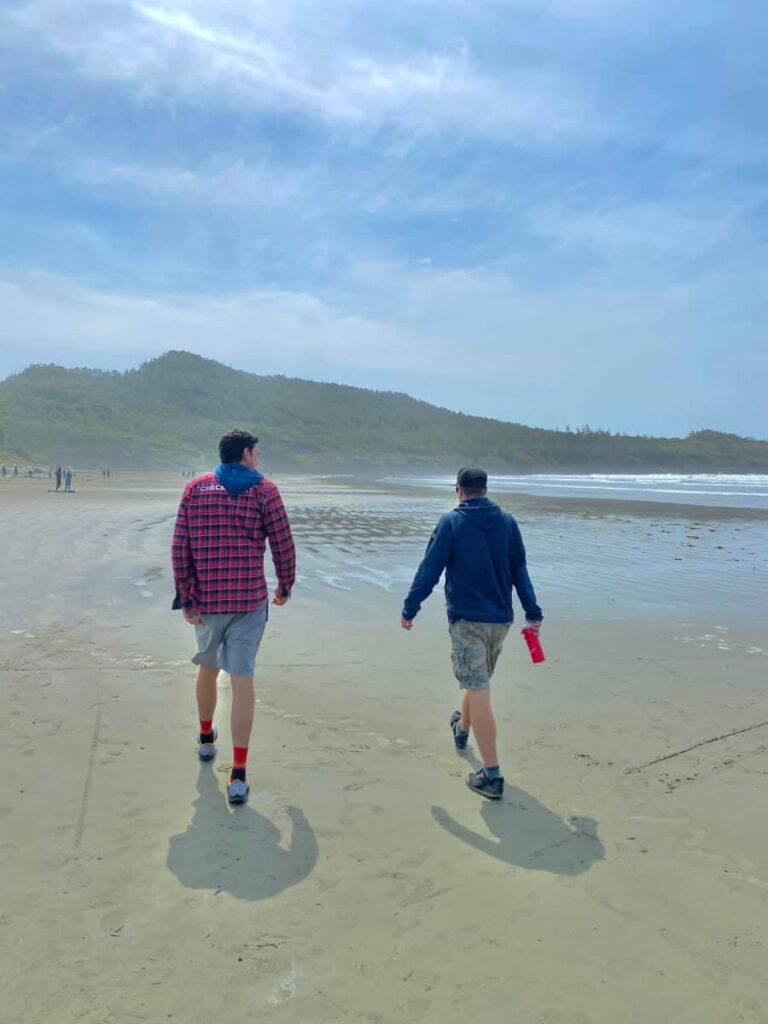 two men walking on cox bay beach in tofino