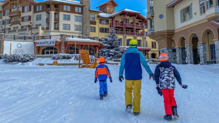 father and sons walking through village in sun peaks resort