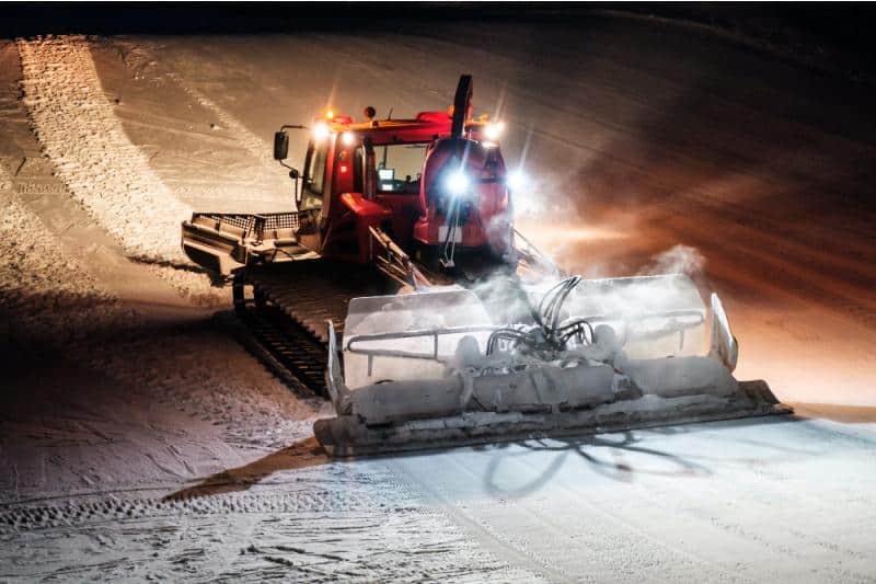 snow groomer at night