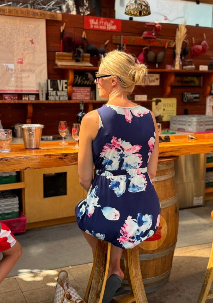 woman in flower dress sitting at bar drinking wine
